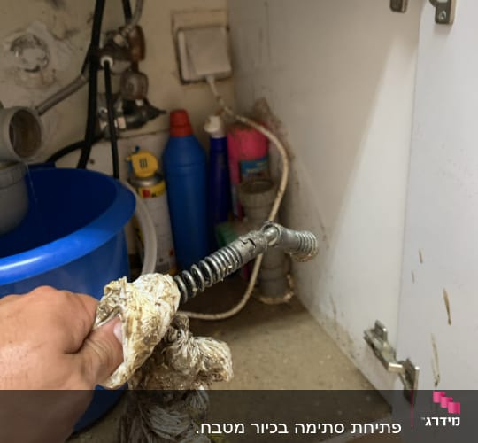 יד מחזיקה קפיץ אינסטלטור מלוכלך מתחת לכיור
